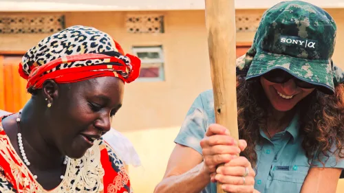 A tourist participating in the making of traditional coffee during a community visit in the Bwindi neighborhood